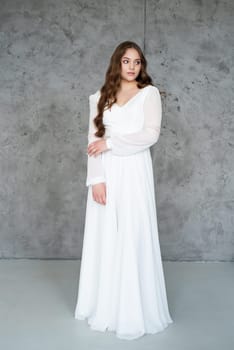 portrait of beautiful young woman in white wedding dress posing in studio