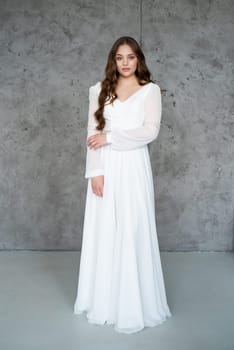 portrait of beautiful young woman in white wedding dress posing in studio