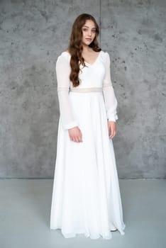 portrait of beautiful young woman in white wedding dress posing in studio