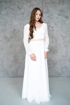 portrait of beautiful young woman in white wedding dress posing in studio