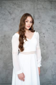 portrait of beautiful young woman in white wedding dress posing in studio