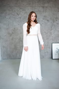 portrait of beautiful young woman in white wedding dress posing in studio