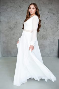 portrait of beautiful young woman in white wedding dress posing in studio