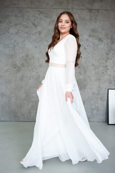 portrait of beautiful young woman in white wedding dress posing in studio