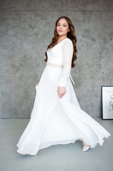 portrait of beautiful young woman in white wedding dress posing in studio