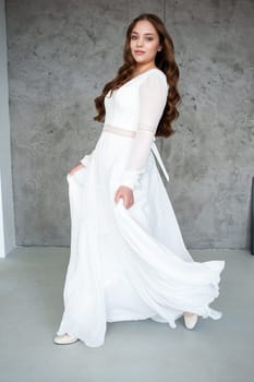 portrait of beautiful young woman in white wedding dress posing in studio