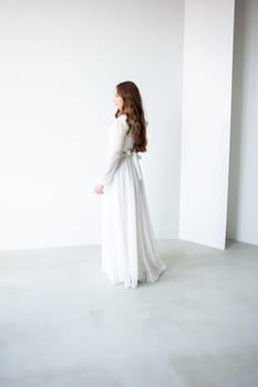 portrait of beautiful young woman in white wedding dress posing in studio