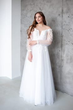 portrait of beautiful young woman in white wedding dress posing in studio