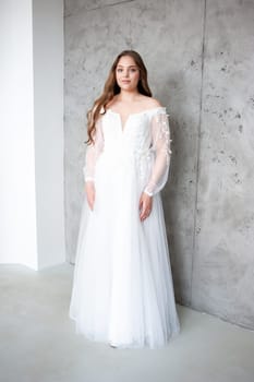 portrait of beautiful young woman in white wedding dress posing in studio