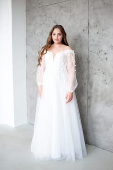 portrait of beautiful young woman in white wedding dress posing in studio