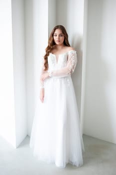 portrait of beautiful young woman in white wedding dress posing in studio