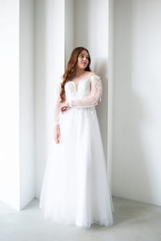 portrait of beautiful young woman in white wedding dress posing in studio