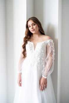 portrait of beautiful young woman in white wedding dress posing in studio