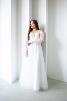 portrait of beautiful young woman in white wedding dress posing in studio