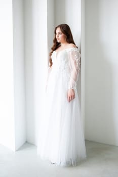 portrait of beautiful young woman in white wedding dress posing in studio