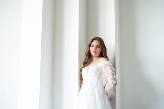 portrait of beautiful young woman in white wedding dress posing in studio