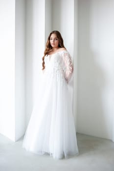 portrait of beautiful young woman in white wedding dress posing in studio