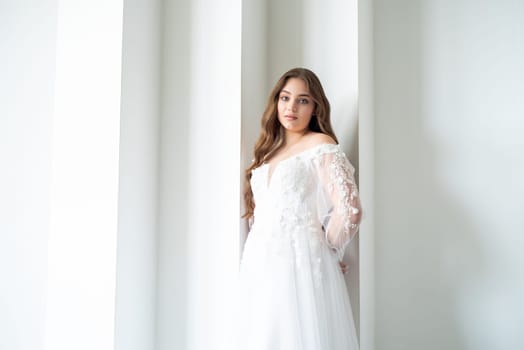 portrait of beautiful young woman in white wedding dress posing in studio