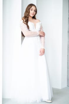 portrait of beautiful young woman in white wedding dress posing in studio