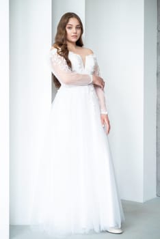 portrait of beautiful young woman in white wedding dress posing in studio