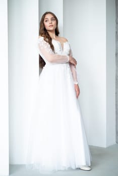 portrait of beautiful young woman in white wedding dress posing in studio