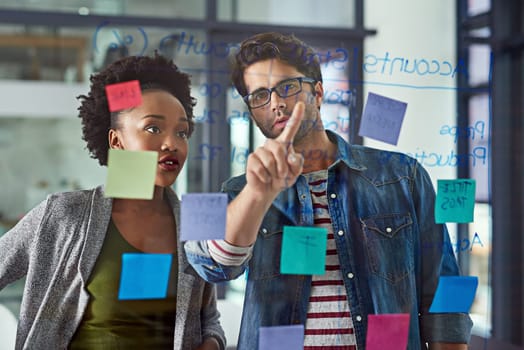 Team, planning and notes on glass in office for schedule or daily routine for tasks or targets. Employees, window and creative designers looking on calendar for projects, timelines and goals