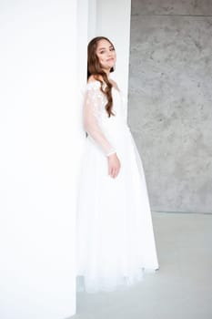 portrait of beautiful young woman in white wedding dress posing in studio