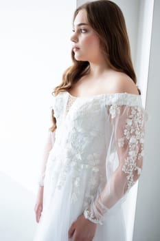 portrait of beautiful young woman in white wedding dress posing in studio