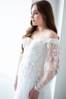 portrait of beautiful young woman in white wedding dress posing in studio