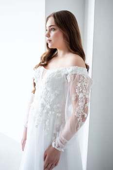 portrait of beautiful young woman in white wedding dress posing in studio