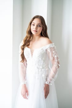 portrait of beautiful young woman in white wedding dress posing in studio