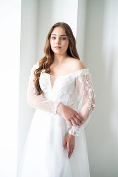 portrait of beautiful young woman in white wedding dress posing in studio