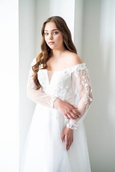 portrait of beautiful young woman in white wedding dress posing in studio