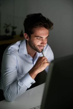 Smile, thinking and businessman with pen by computer for email, internet and working late in office for corporate career. Happiness, desk and lawyer with technology for communication in workspace.