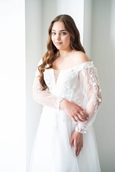 portrait of beautiful young woman in white wedding dress posing in studio