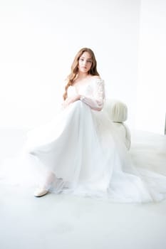 portrait of beautiful young woman in white wedding dress posing in studio