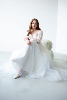 portrait of beautiful young woman in white wedding dress posing in studio