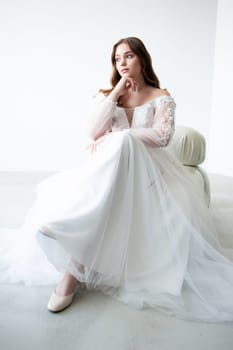 portrait of beautiful young woman in white wedding dress posing in studio