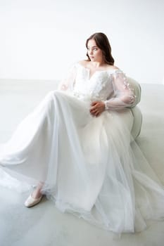 portrait of beautiful young woman in white wedding dress posing in studio