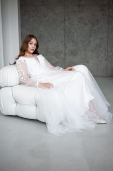 portrait of beautiful young woman in white wedding dress posing in studio