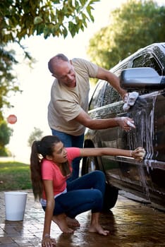 Father, girl and car washing for cleaning, learning responsibility and development outdoor. Child, kid or children and dad for busy routine, childhood and cute for soap water or fun on weekend.