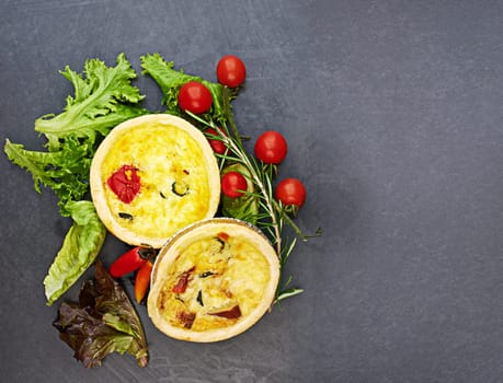 Tart, vegetables and food on dark background for bakery with pastry, nutrition and brunch meal. Pie, carbs and tomato on countertop for breakfast cooking, green color and healthy eating with hungry.