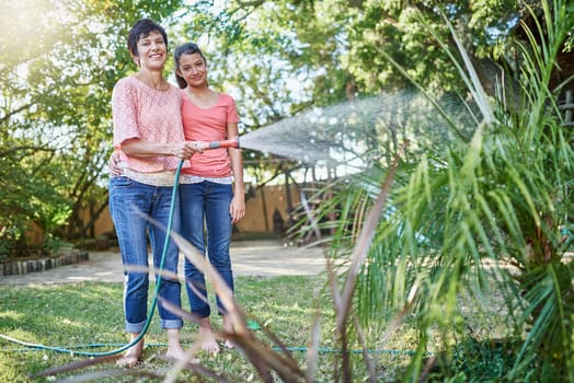 Garden, watering and portrait of mother and child in backyard for natural environment, agriculture and nature. Family, happy and mom with teenage girl with water hose for plants, flowers and grass.