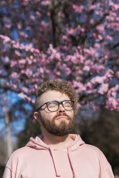 Man allergic enjoying after treatment from seasonal allergy at spring. Portrait of happy bearded man smiling in front of blossom tree at springtime. Spring blooming and allergy concept. Copy space, vertical.