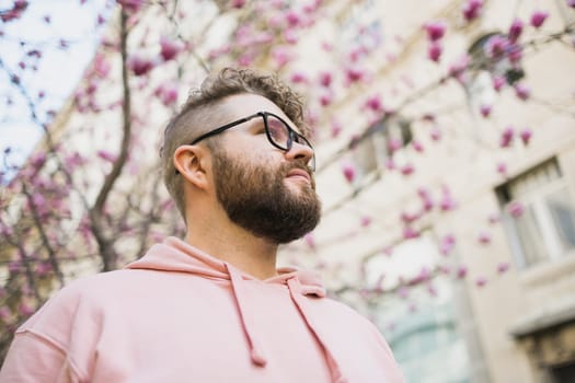 Spring fashion style. Male sexuality. Bearded man portrait on blooming flower tree background. Enjoy good weather springtime. Copy space.