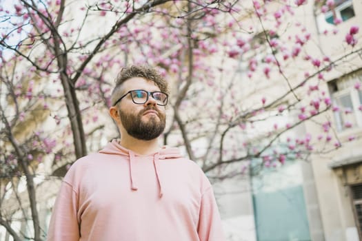 Spring fashion style. Male sexuality. Bearded man portrait on blooming flower tree background. Enjoy good weather springtime. Copy space.