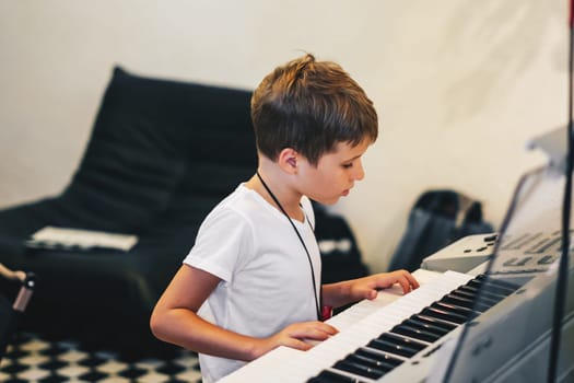 Young boy Portrait sitting at digital piano Playing keyboard focused kid activity indoors press on Key learning to play music room Hobby.