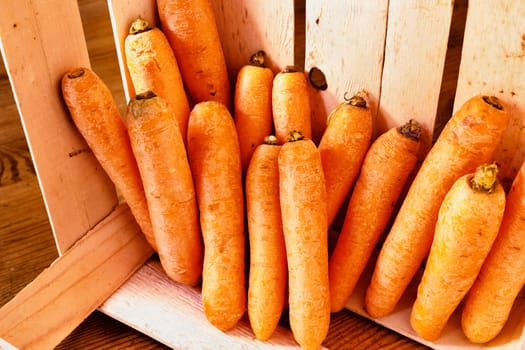 Bunch of orange carrots in wooden box on wooden table , 
