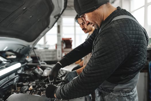 Two male mechanics repairing car in car service close up