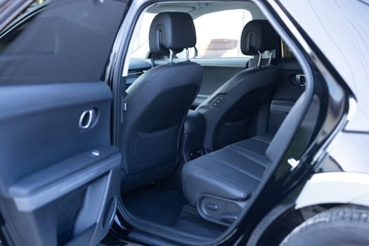 Rear leather passenger seats in modern lux electric car. Black leather car passenger seat. Control unit with electric seat adjustment for rear passengers in luxury car. Modern car interior detail.